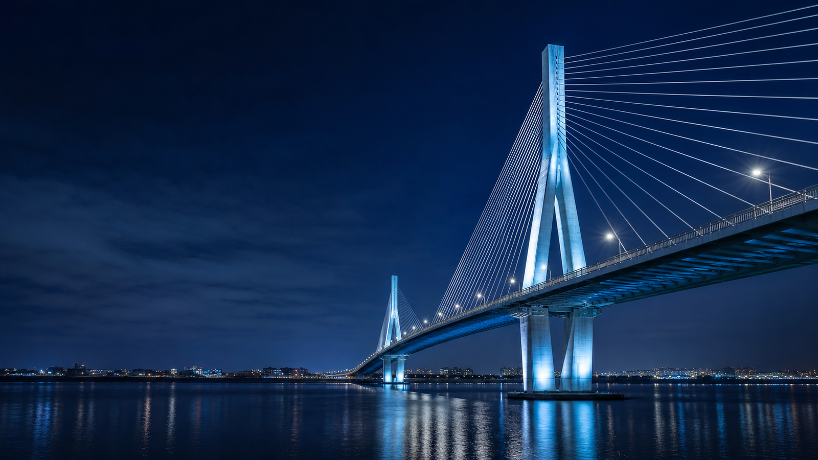 Illuminated bridge spanning a river at blue hour